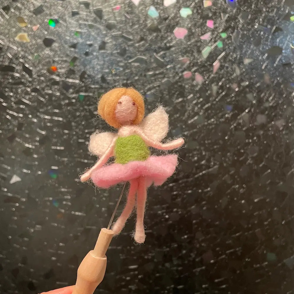 Small fairy figurine on a stick against a textured black background