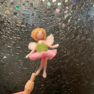 Small fairy figurine on a stick against a textured black background