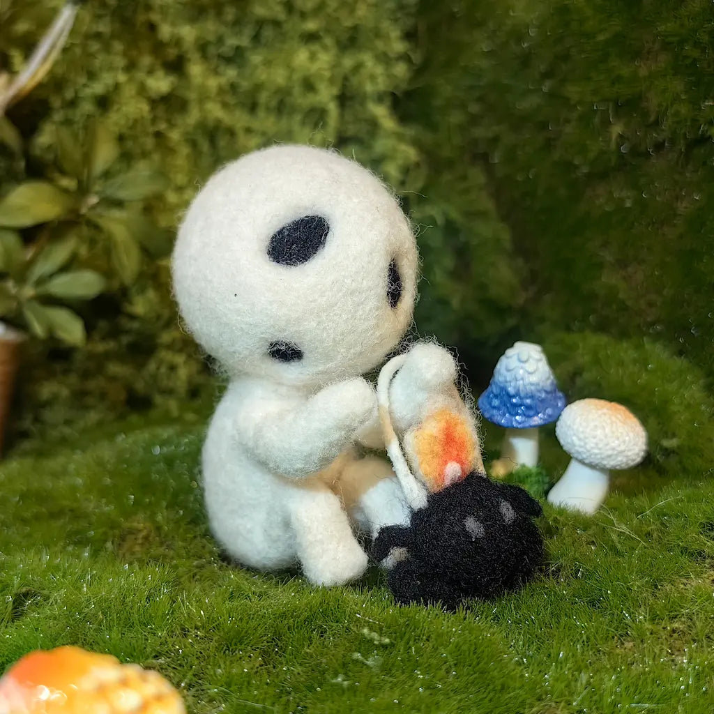 Handmade white wool Lantern Sprite holding a spider lantern beside miniature mushrooms