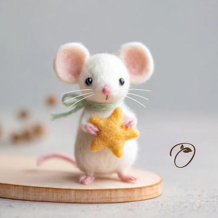 Front view of an ivory felt mouse holding a yellow star, wearing a sage-green scarf, with pink ears, paws, and a small pink nose.