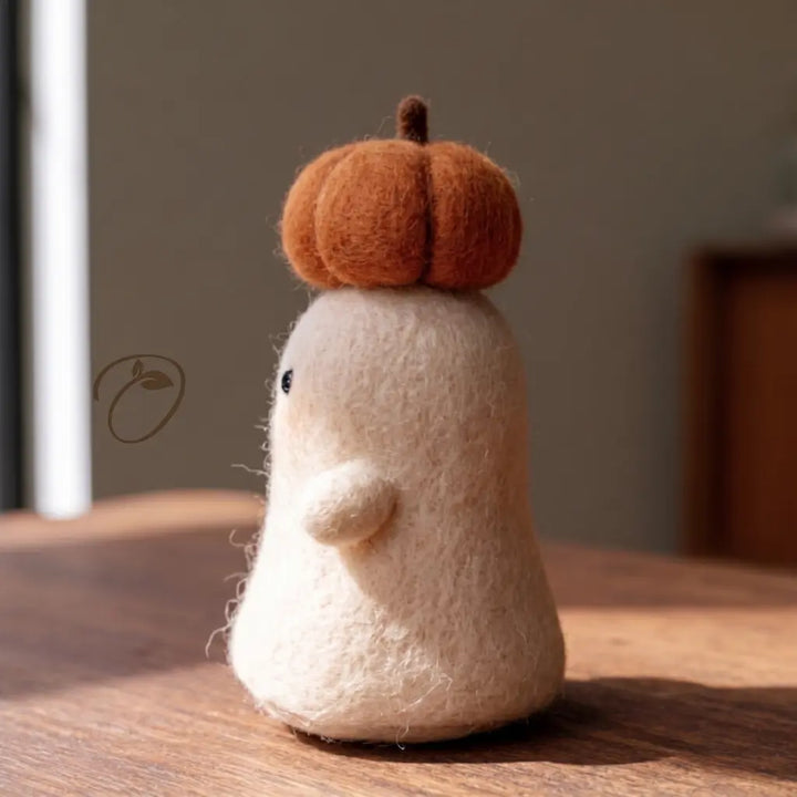 Side view of the Pumpkin Crown Ghost felt figurine, showing its rounded arm and sculpted orange pumpkin.