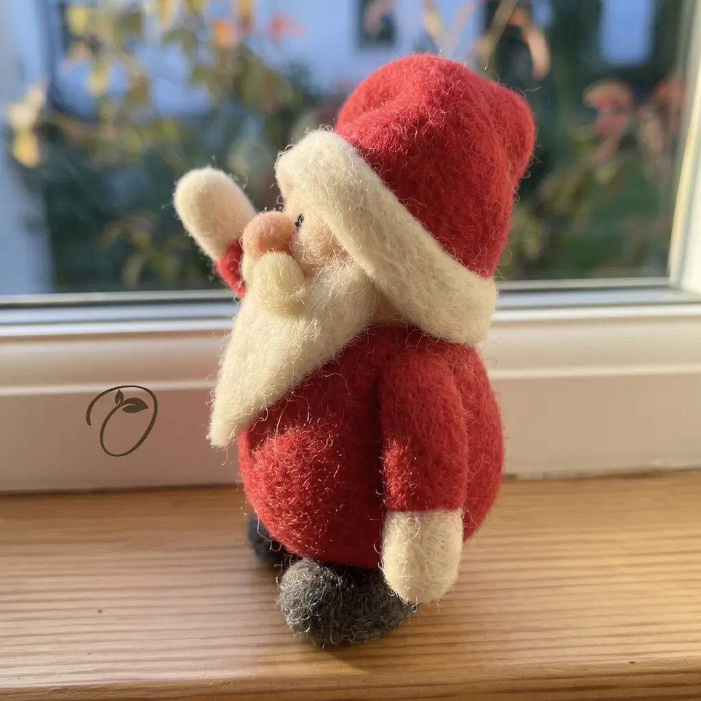 Side view of Merry Hello Santa felt figurine showing the folded red hat, cream brim, raised mitten and tapered beard.