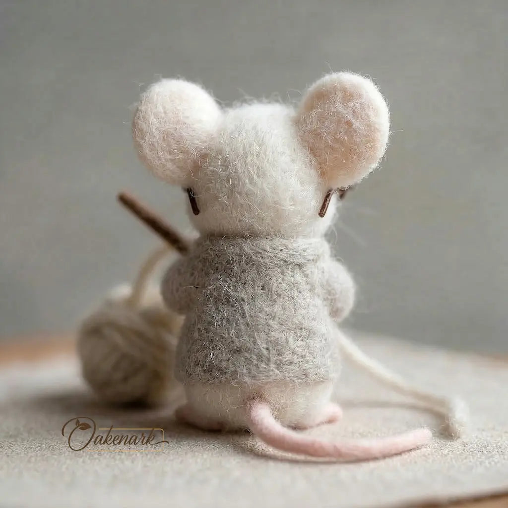 Felted mouse toy with yarn on a neutral background