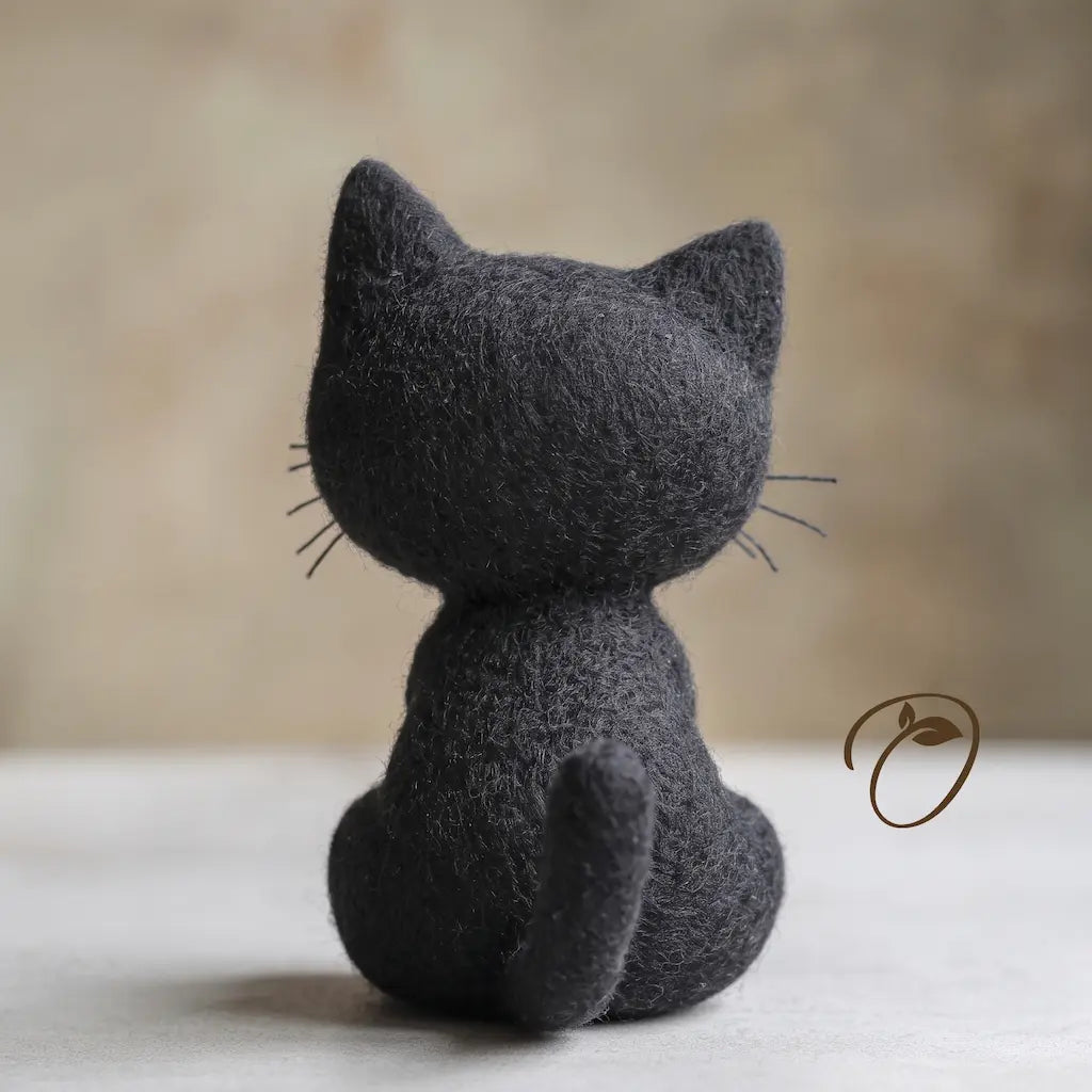 Back view of seated black cat felt figurine showing its rounded head, pointed ears and curved tail