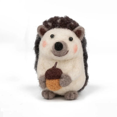 Stuffed hedgehog toy holding an acorn on a white background
