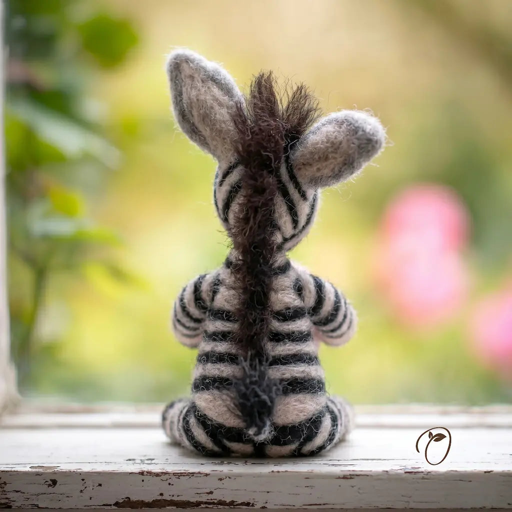 Zebra toy on a windowsill with a blurred outdoor background