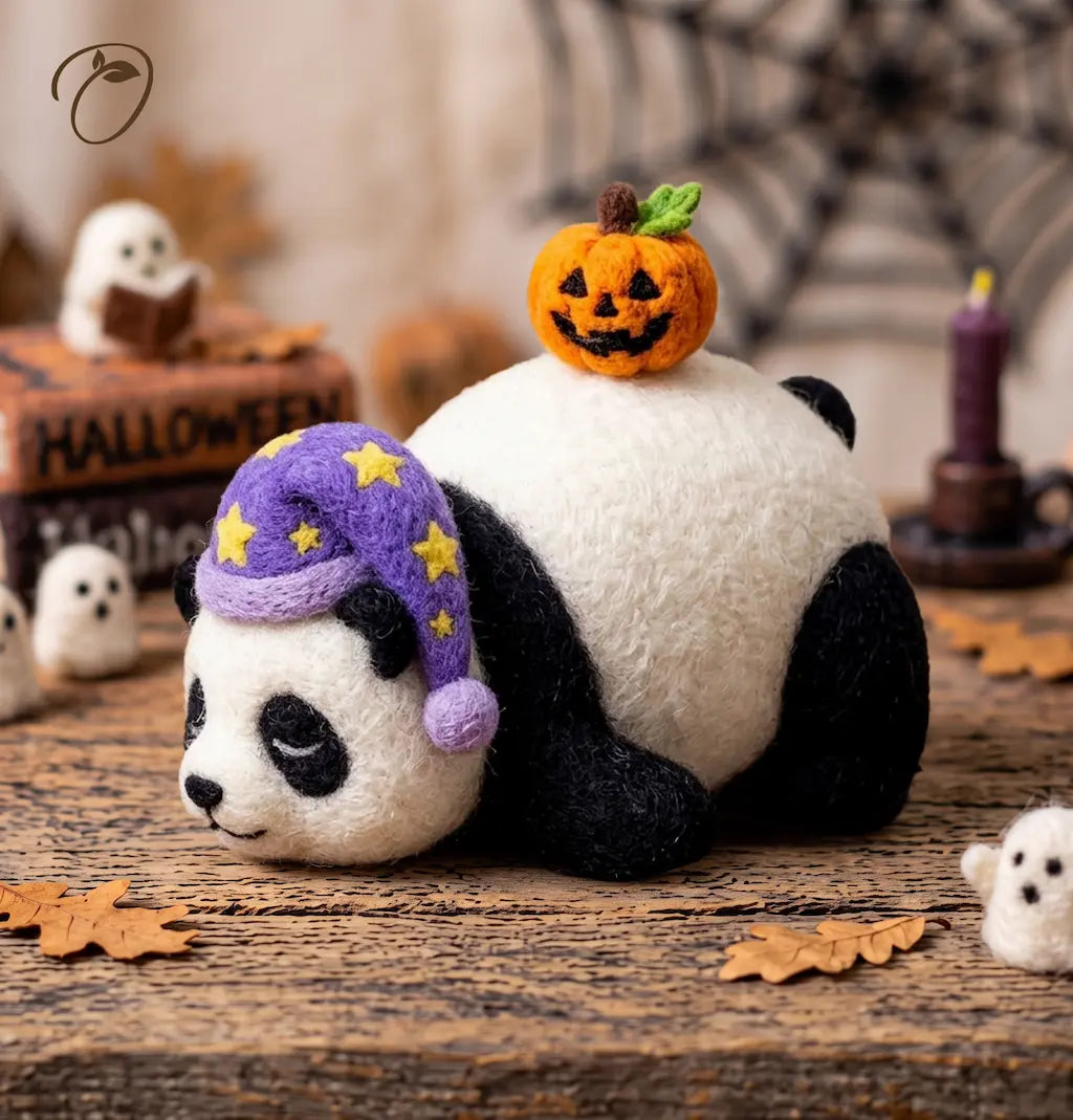Three-quarter view of a sleeping felt panda wearing a purple starry nightcap with an orange jack-o’-lantern on its back