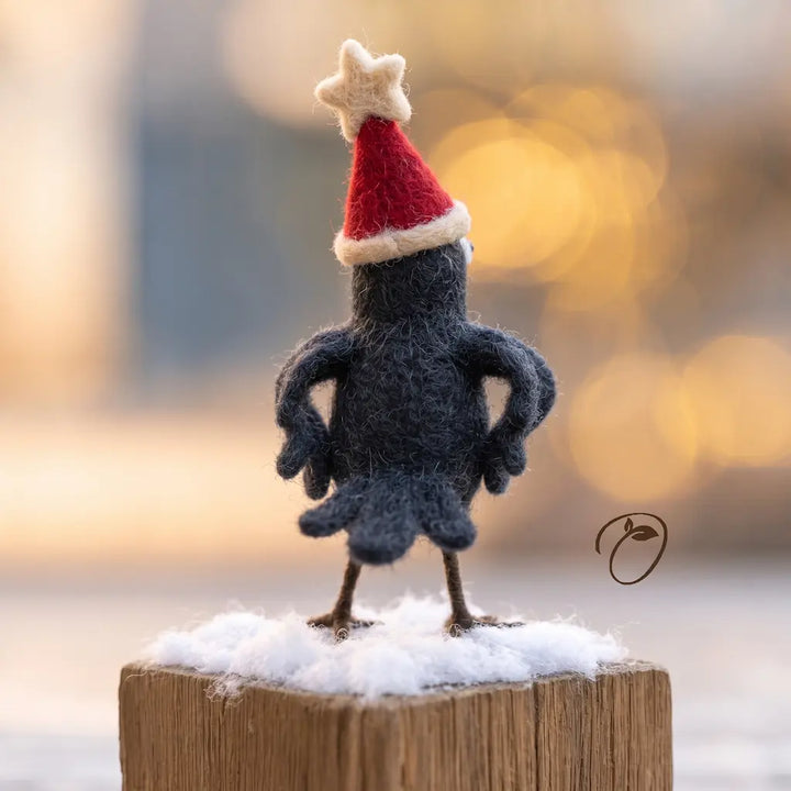 Rear view of a black felt crow showing curved wings, layered tail feathers and a red hat topped with a cream star.
