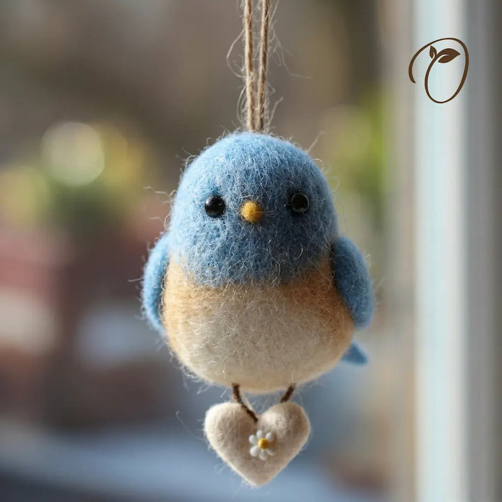 Felted blue and beige bird ornament hanging against a blurred background