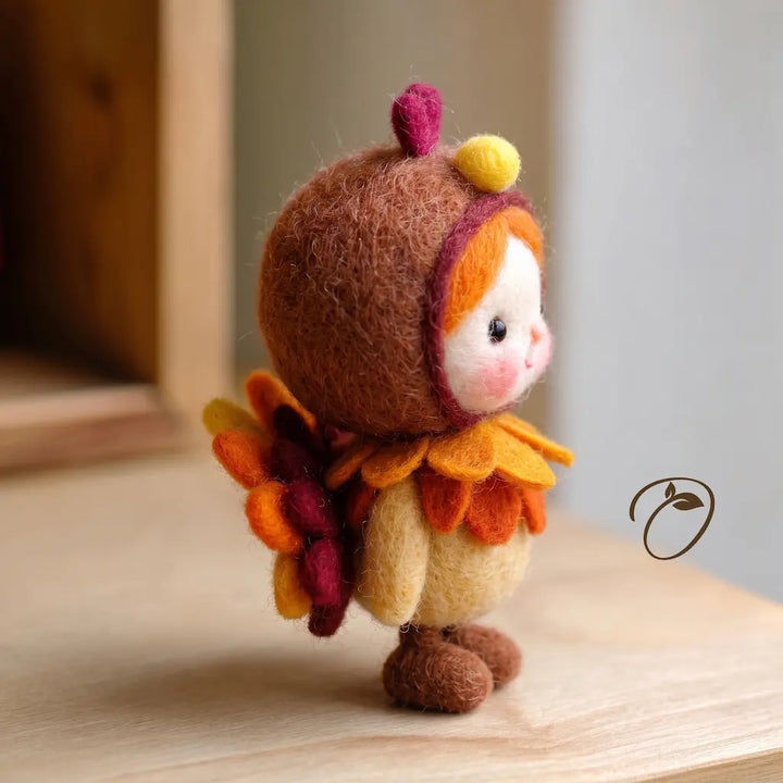 Side view of a felt turkey costume figurine showing a rosy cheek, layered autumn collar, cream body, and colorful tail feathers.