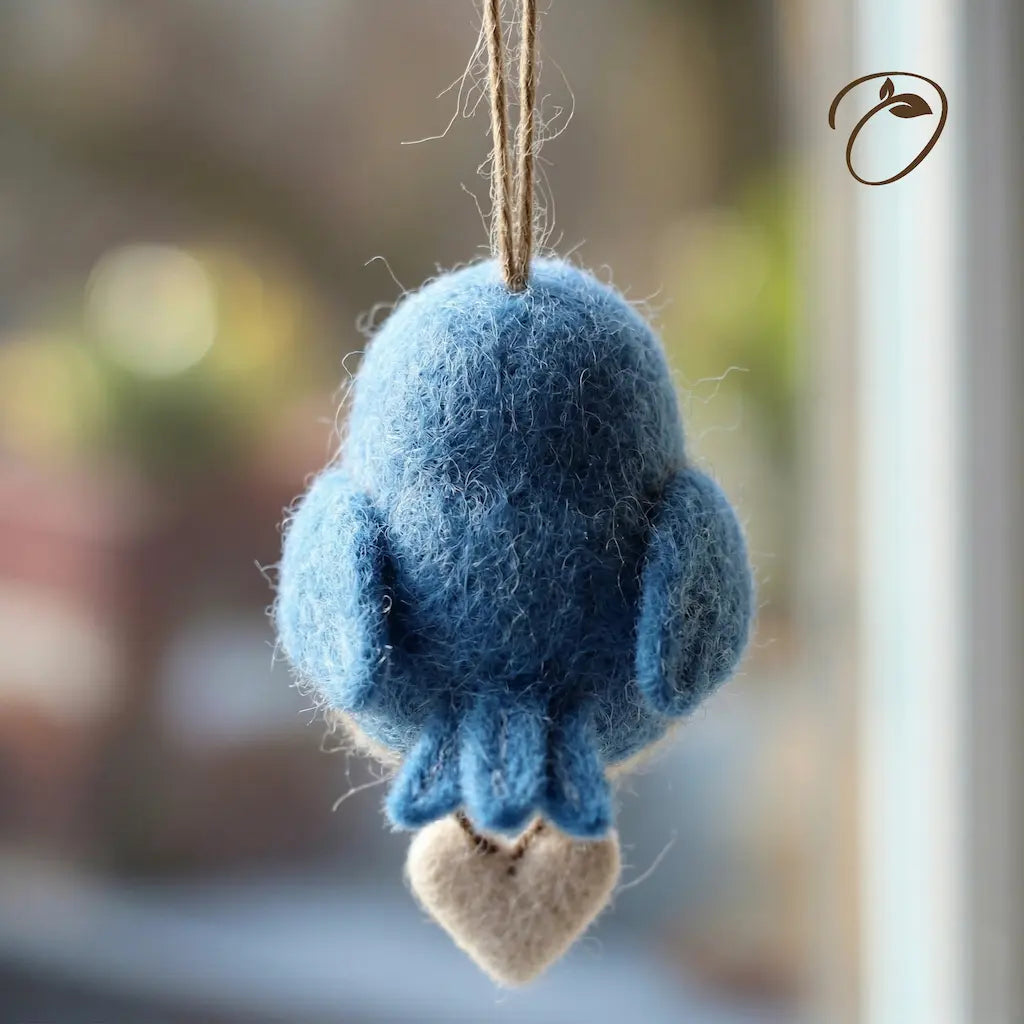 Blue felted bird ornament hanging against a blurred background
