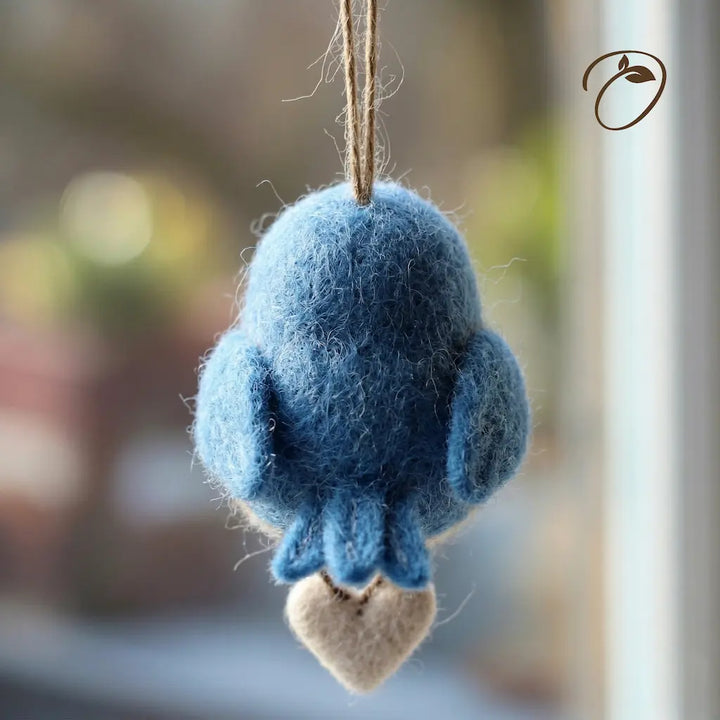 Blue felted bird ornament hanging against a blurred background