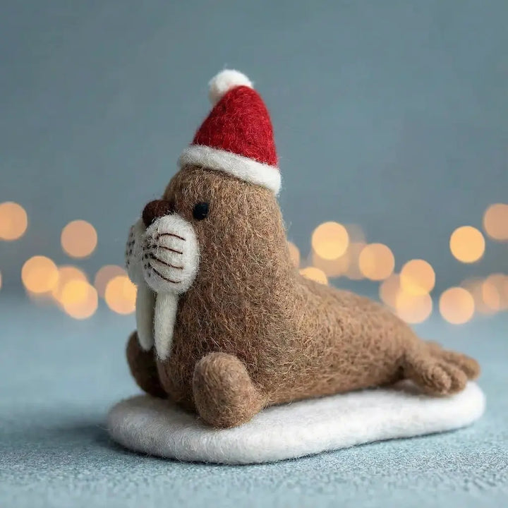 Stuffed animal walrus wearing a Santa hat with a blurred light background