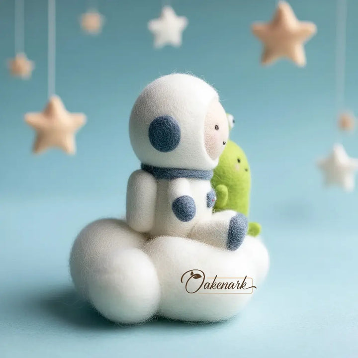 Felt toy astronaut holding a green alien with hanging stars on a light blue background, featuring the brand &