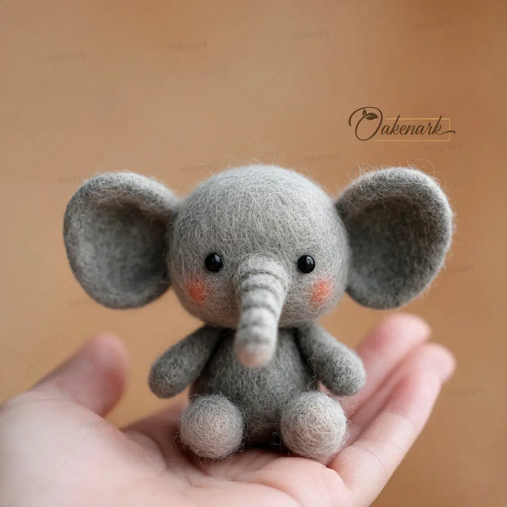 Small gray elephant plush toy held in a hand against a brown background