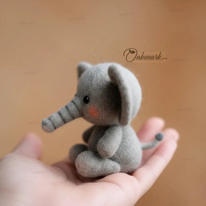 Small gray elephant plush toy held in a hand against a brown background