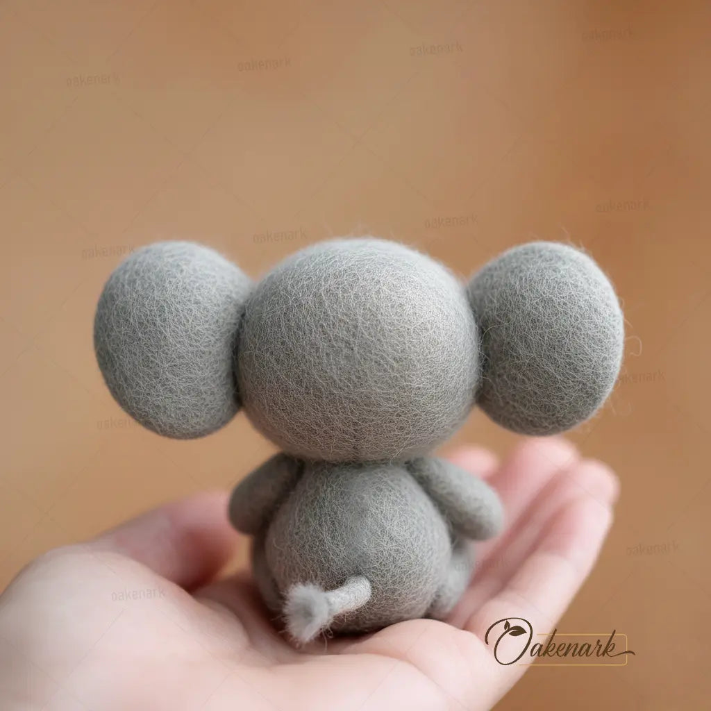 Small gray plush toy held in a hand against a brown background