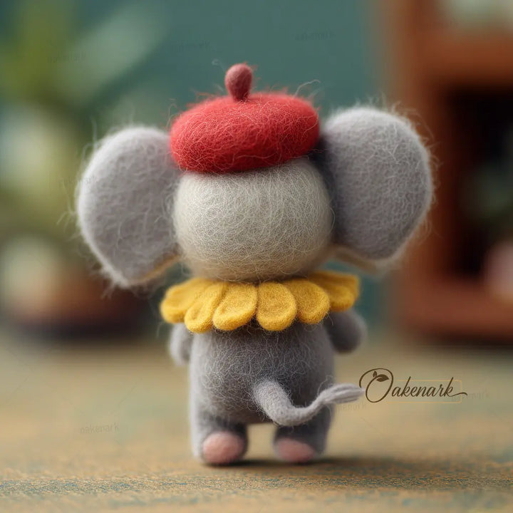 Small elephant figurine with a red hat and yellow collar on a textured surface