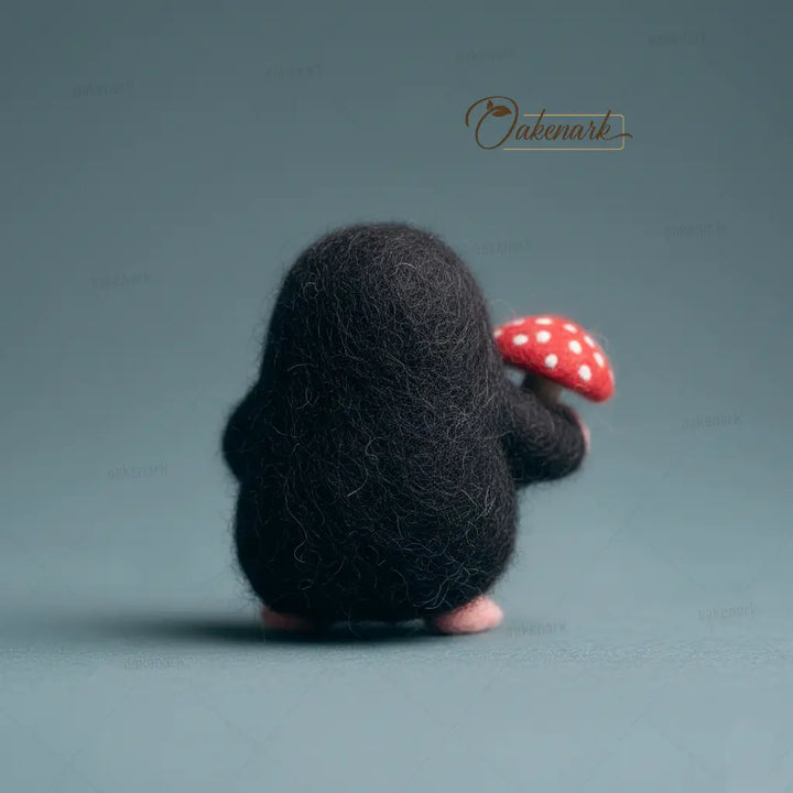 Small black creature holding a red mushroom with white spots on a gray background