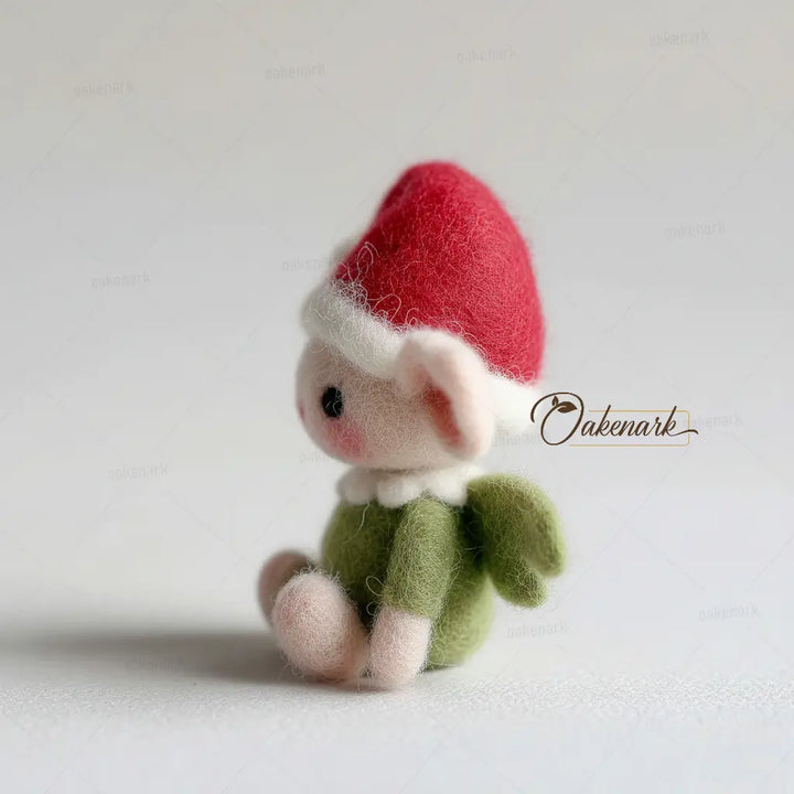 Small felt gnome figurine with a red hat and green outfit on a light background, featuring the brand &
