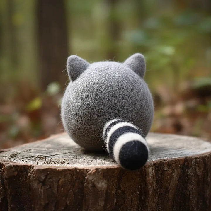 Plush raccoon toy on a wooden stump with a blurred forest background