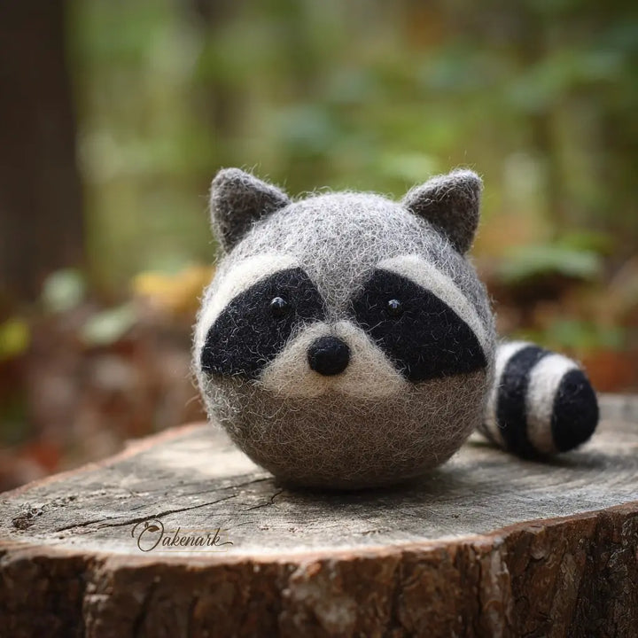 Felt raccoon toy on a wooden log with a natural background