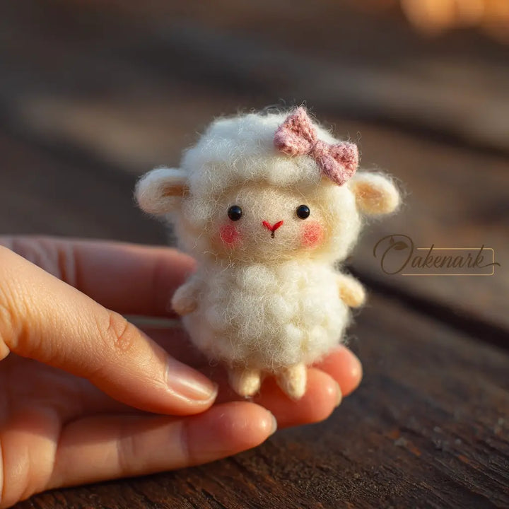 Small white toy sheep with a pink bow held in a hand on a wooden surface
