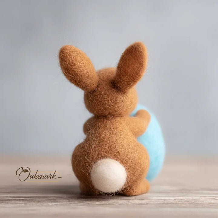 Brown felted bunny with a blue ball on a wooden surface
