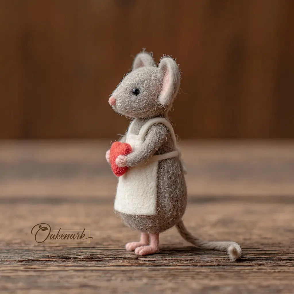 Stuffed mouse toy holding a red heart on a wooden surface with &