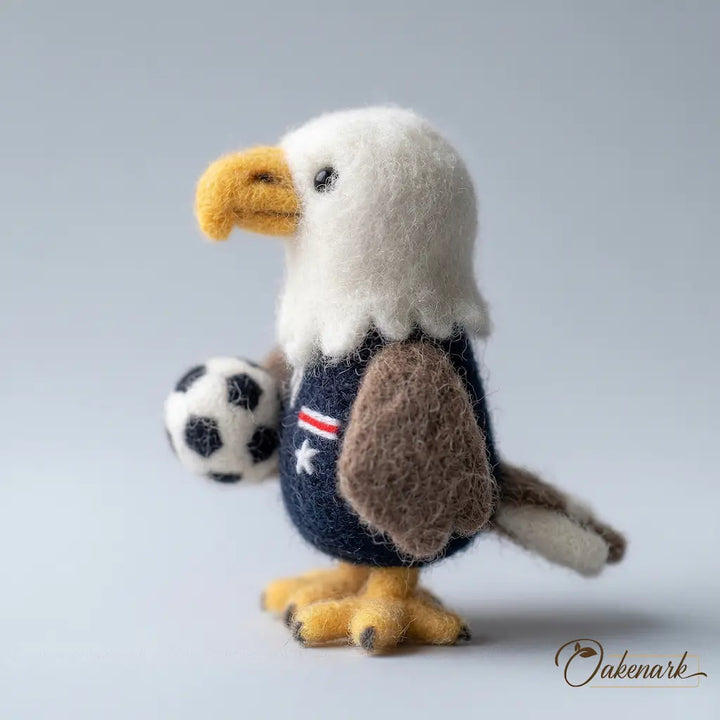 Stuffed toy eagle holding a soccer ball on a gray background