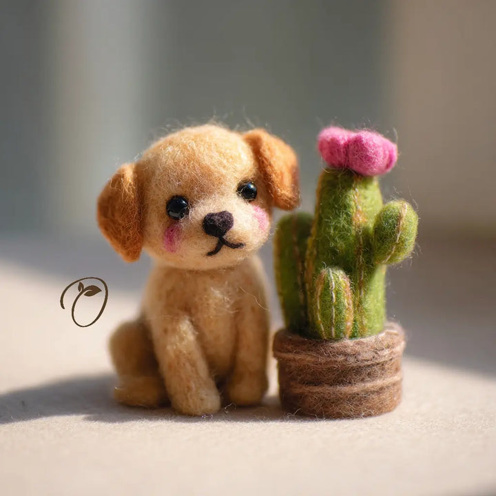 Felted toy dog sitting next to a felted cactus with pink flower on a neutral background