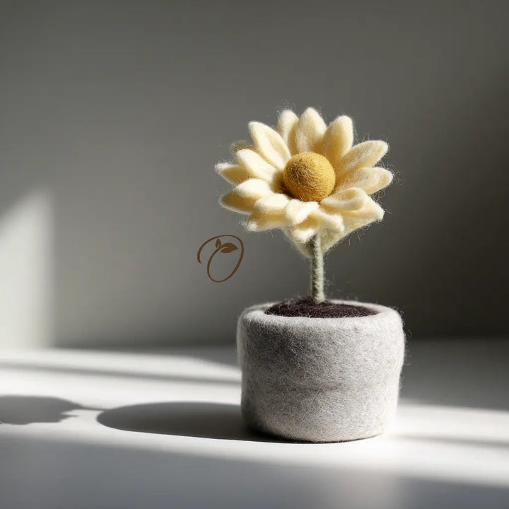 Felted sunflower in a gray felt pot on a light surface with a neutral background