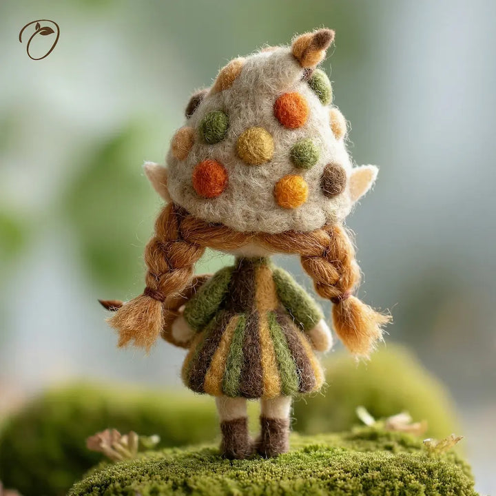 Small figurine with a polka dot hat and braided hair standing on a green surface.
