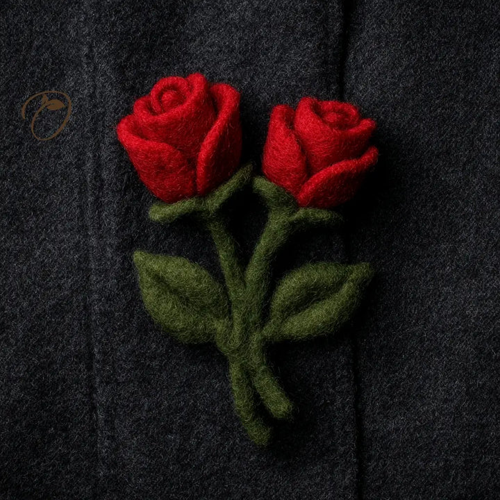 Two red roses with green leaves on a dark fabric background