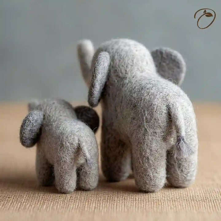 Two small gray elephant toys facing each other on a textured surface with a neutral background.