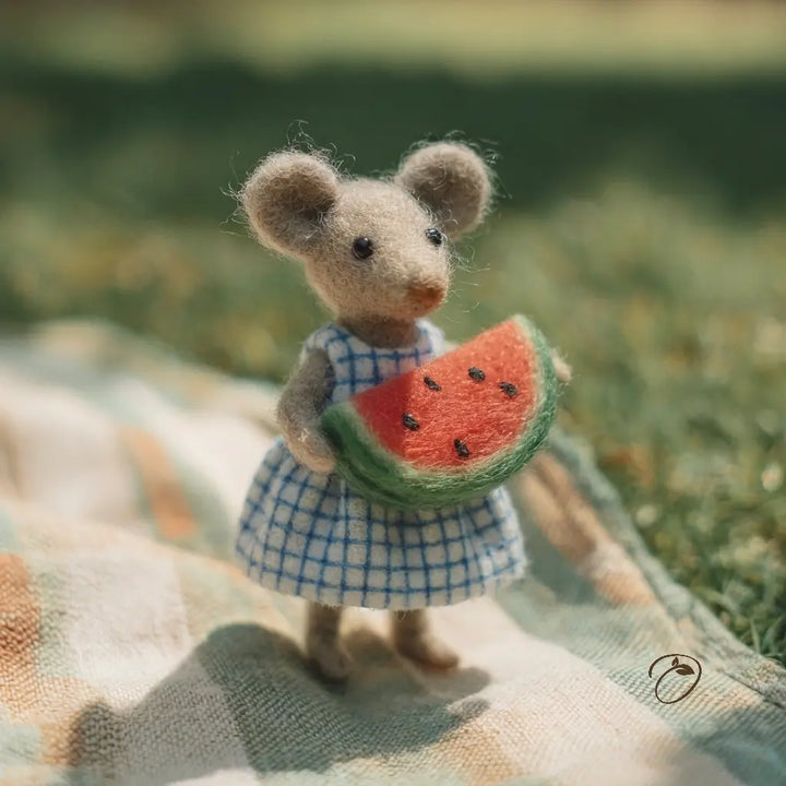 Textile mouse holding a watermelon slice on a checkered cloth with a blurred natural background