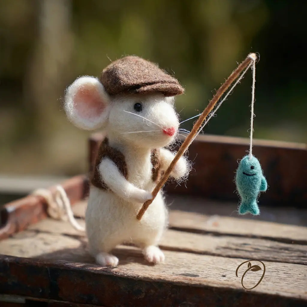 Toy mouse in a cap holding a fishing rod with a fish on a wooden surface