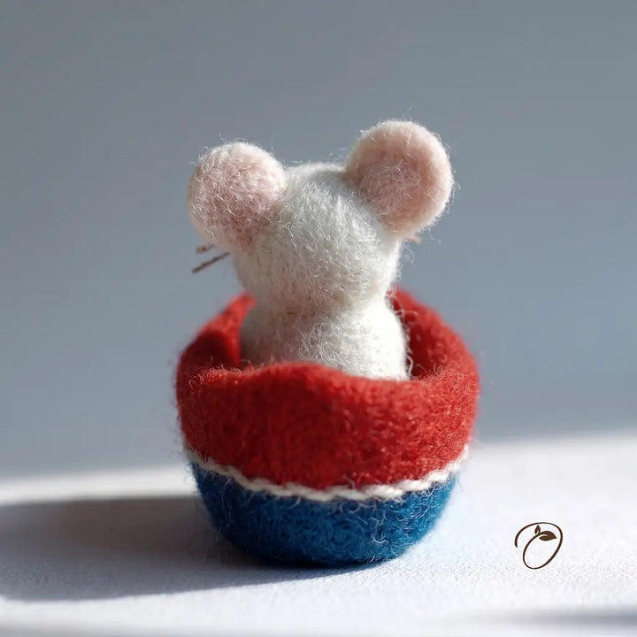 Small felt mouse inside a red and blue striped bowl on a light background