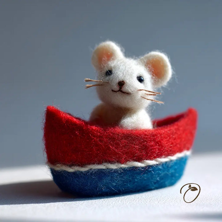 Felted mouse in a red and blue boat on a light background