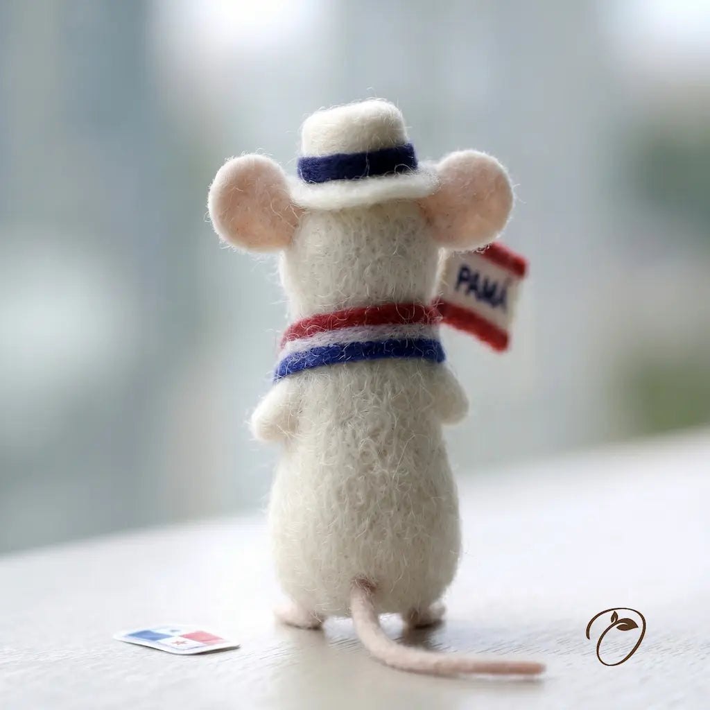 Felted mouse toy wearing a hat and holding a flag on a light background