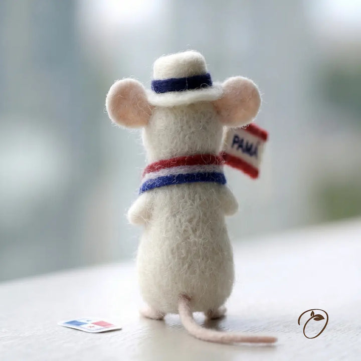 Felted mouse toy wearing a hat and holding a flag on a light background