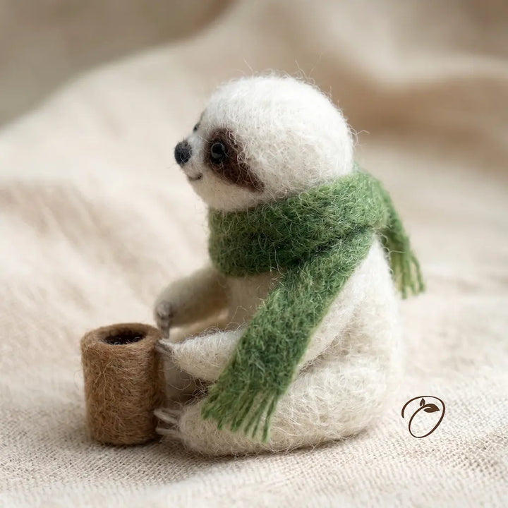 Stuffed animal sloth wearing a green scarf on a beige fabric background