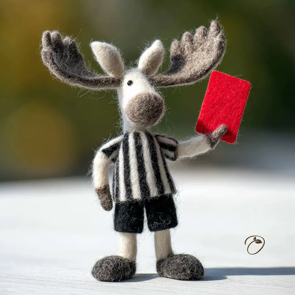 Toy moose in a referee outfit holding a red card against a blurred natural background