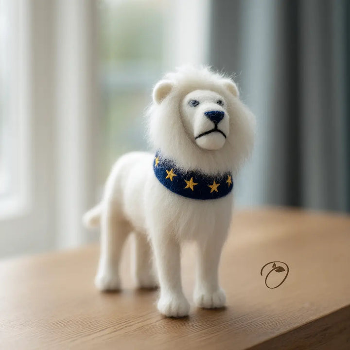White lion figurine with a blue collar featuring yellow stars on a wooden surface.