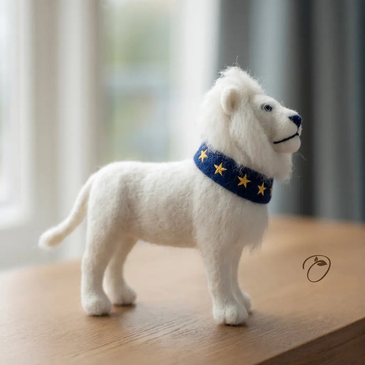 White lion figurine wearing a blue collar with yellow stars on a wooden surface.