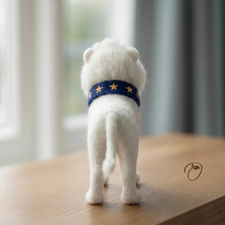White teddy bear with a blue star-patterned collar on a wooden surface.