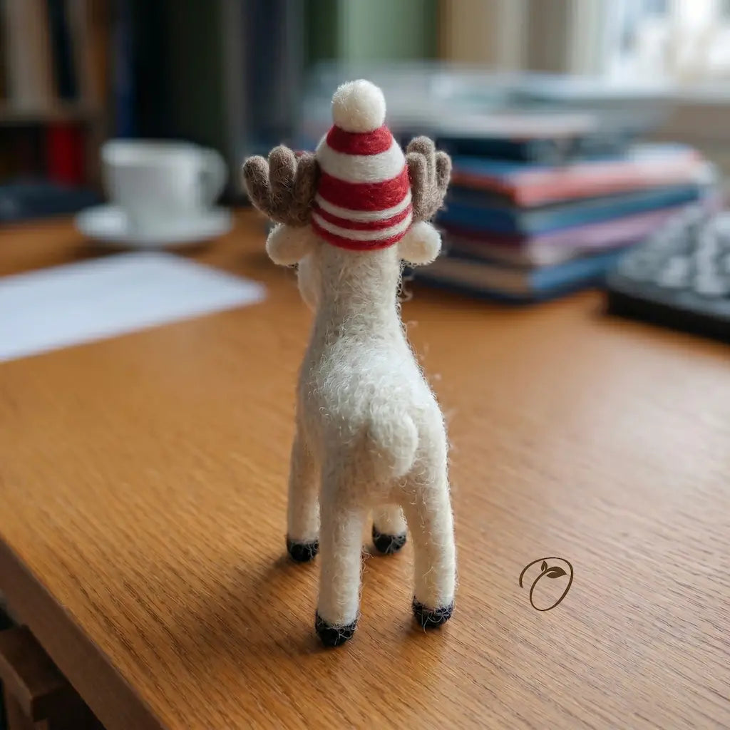 Small white reindeer figurine wearing a red and white striped hat on a wooden surface.