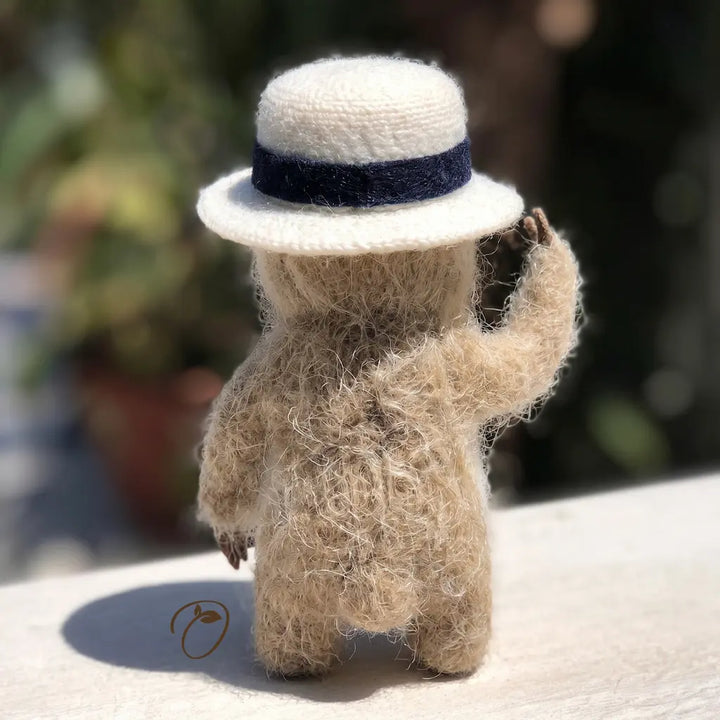 Knitted animal figure wearing a hat with a blurred natural background