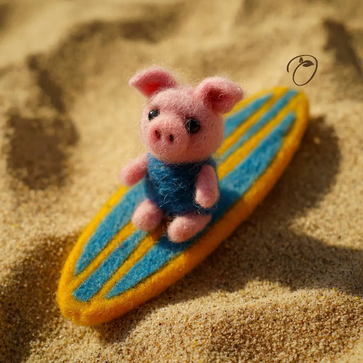 Toy pig on a surfboard in sand