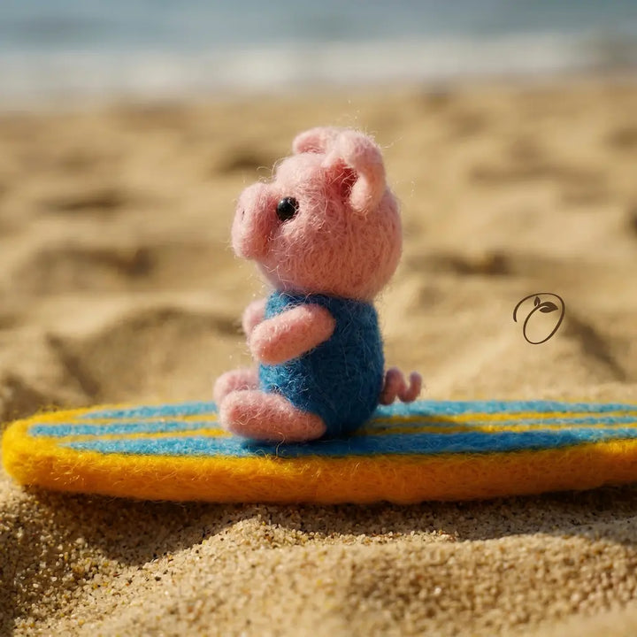 Pink plush toy mouse on a yellow and blue surfboard on a sandy beach